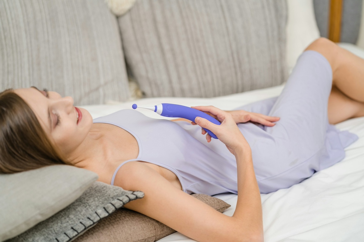 donna sorridente sdraiata sul divano con sex toy Lovense