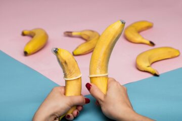 mani di donna con banane con preservativi