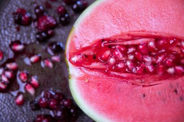 metà di melograno aperto con chicchi sparsi