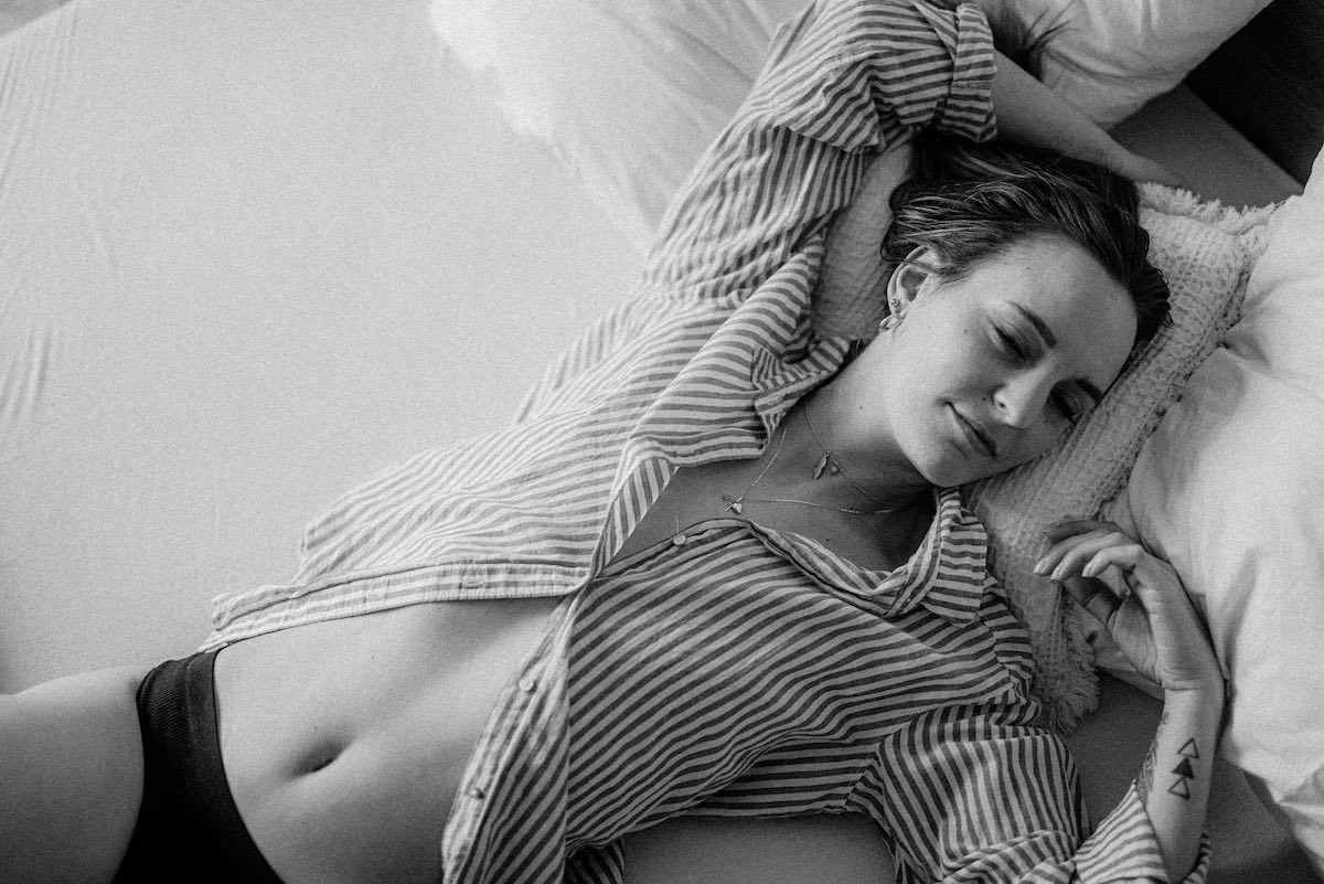 foto in bianco e nero di giovane donna sorridente e soddisfatta sul letto