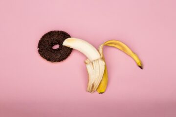 Metafora visiva di esplorazione sessuale femminile con banana su sfondo viola