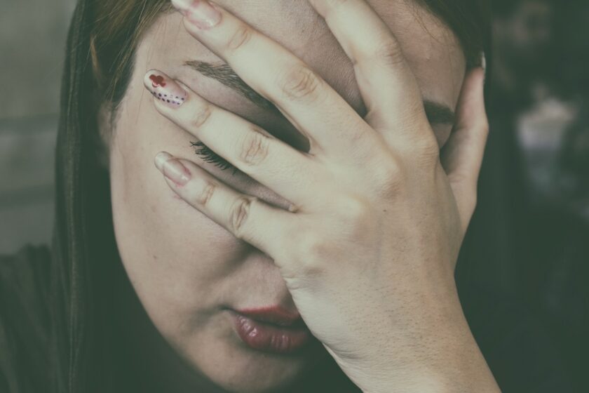 Mani di una donna appoggiate alla testa, espressione stanca e delicata