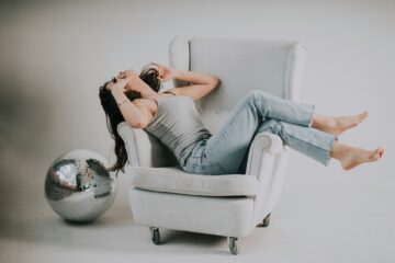 Donna seduta su un divano, corpo rilassato, sguardo contemplativo, atmosfera intima