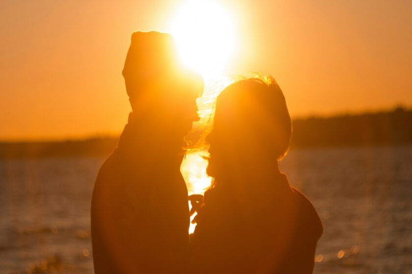 Coppia abbracciata su una spiaggia al tramonto, in connessione emotiva