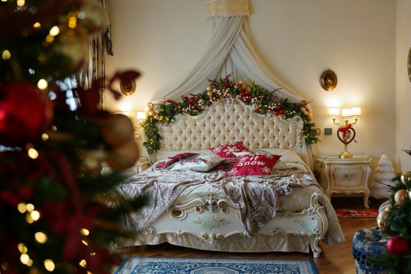 Letto con coperte rosse e luci natalizie in una stanza calda e accogliente, con albero di Natale