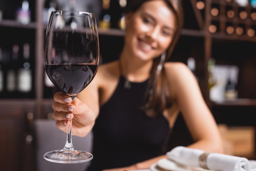Donna sorridente che brinda da sola con un calice di vino, atmosfera serena e rilassata