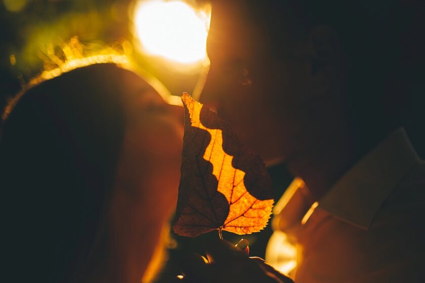 Immagine a tema dirty talk: coppia in un momento di complicità con un sussurro all’orecchio, luce calda e atmosfera intima.