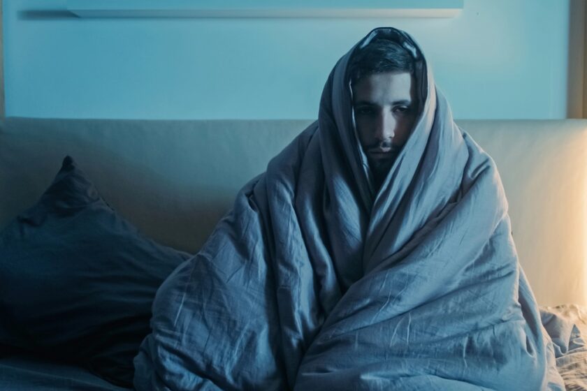 Immagine a tema eccitazione che va e viene: persona seduta sul letto in atteggiamento pensieroso, luce calda e atmosfera serale.