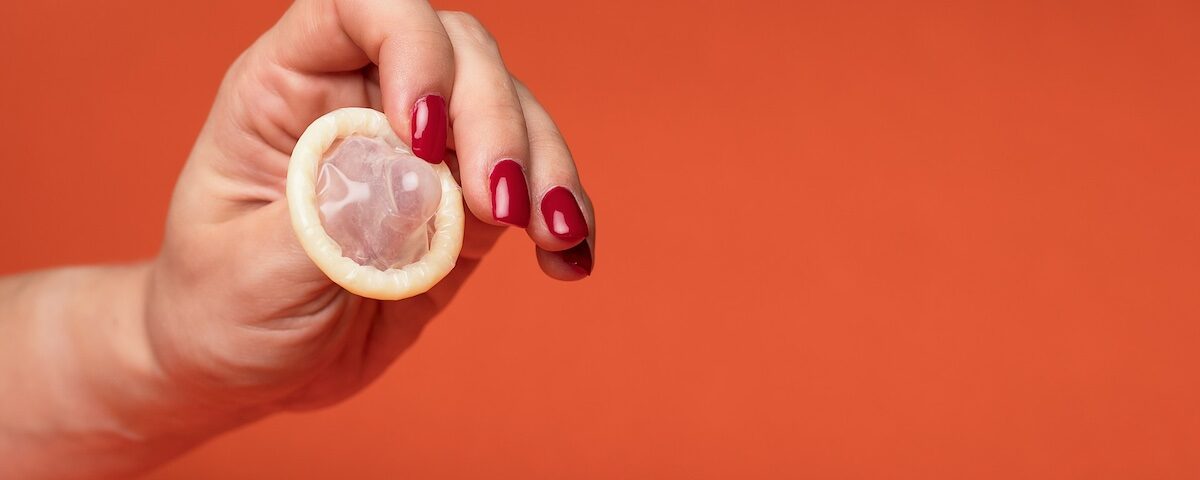 Mano che tiene un preservativo, immagine rappresentativa di sesso sicuro e uso corretto del preservativo.