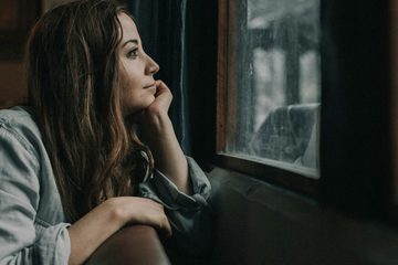 Donna seduta sul davanzale di una finestra.